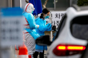 A medical staff member in protective gear prepares to take samples from a visitor in a car at a ‘drive-thru’ testing center for the novel coronavirus disease of COVID-19 in Yeungnam University Medical Center in Daegu