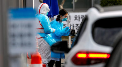 A medical staff member in protective gear prepares to take samples from a visitor in a car at a ‘drive-thru’ testing center for the novel coronavirus disease of COVID-19 in Yeungnam University Medical Center in Daegu