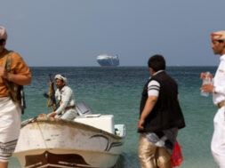 FILE PHOTO: Armed men stand on the beach as the Galaxy Leader commercial ship, seized by Yemen’s Houthis last month, is anchored off the coast of al-Salif