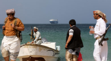 FILE PHOTO: Armed men stand on the beach as the Galaxy Leader commercial ship, seized by Yemen’s Houthis last month, is anchored off the coast of al-Salif